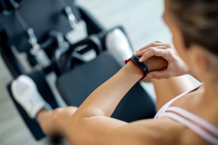 Training Heart Rate Calculator: Calculate Heart Rate Zones for Your Endurance Training Athlete checking her training heart rate on a fitness tracker during a workout