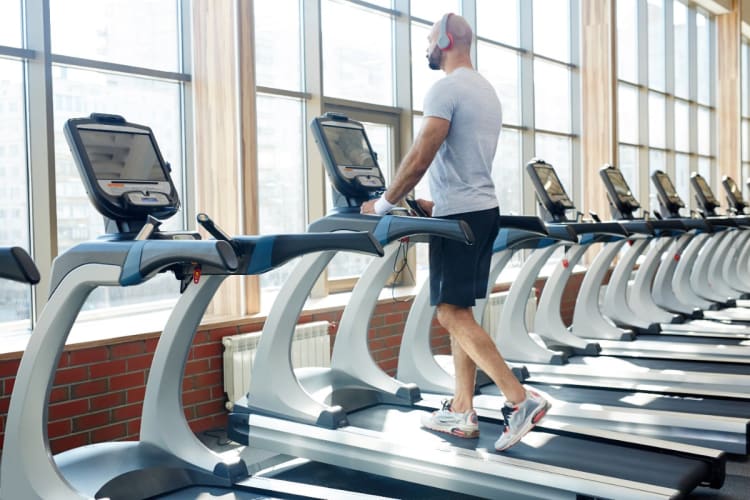 Mann trainiert auf einem Laufband mit Steigung im Fitnessstudio