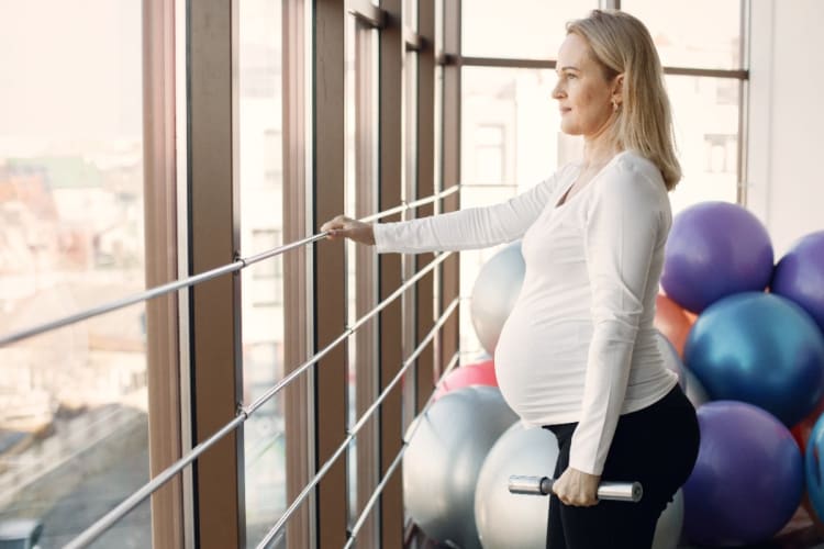 Pregnancy Weight Calculator: Recommended Weight Gain with a Weekly Plan Pregnant woman working out at the gym
