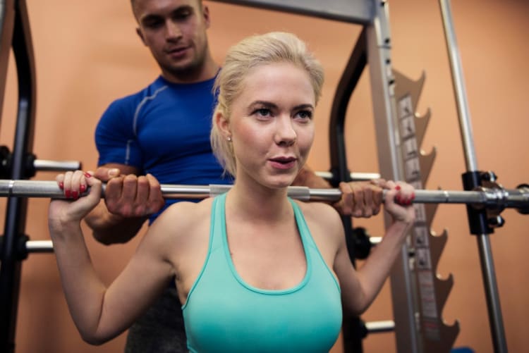 RPE-Rechner: Anstrengung und Prozent vom Maximum umrechnen Sportlerin bei einer anstrengenden Kniebeuge im Fitnessstudio