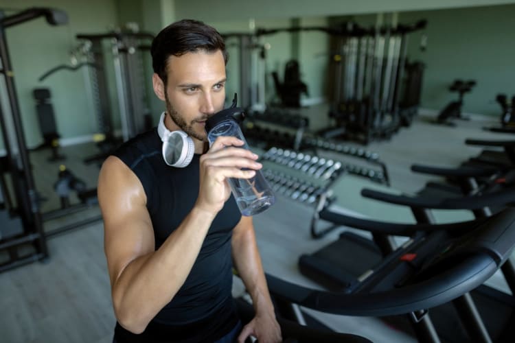 Hydration-Rechner: Trinkmenge aus Grundbedarf und Schweißverlust berechnen Sportler trinkt nach dem Lauftraining Wasser aus einer Flasche