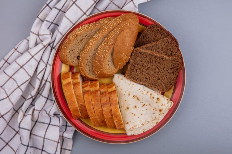 Glykämische Last berechnen: gleiche Menge Brot, sehr unterschiedliche Blutzuckerwirkung Verschiedene Brotsorten von Weißbrot bis Vollkornbrot auf einem Teller