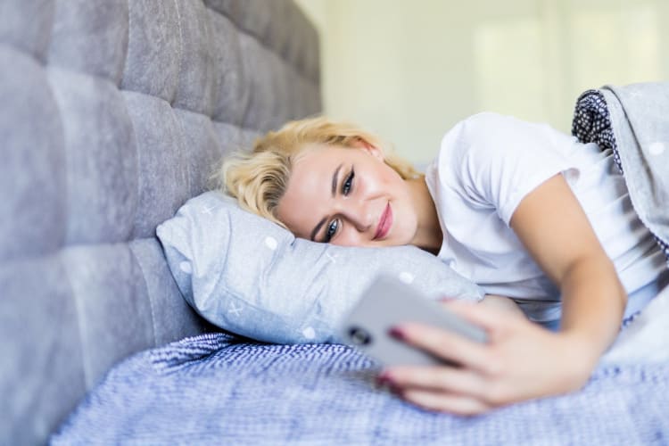 Person misst morgens im Bett ihre Herzfrequenz mit dem Smartphone